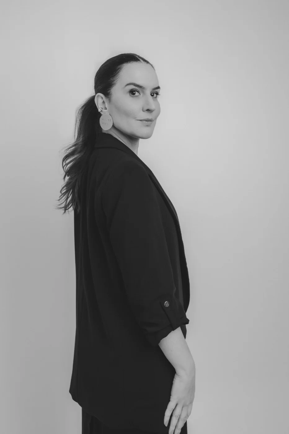 Dra. Fernanda Cavallieri de blazer preto, olhando por cima do ombro, em preto e branco